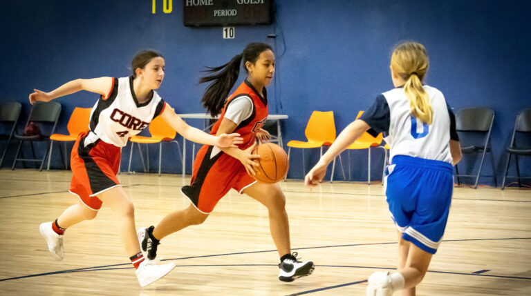 Sports 5 Girl Drives The Basketball Past Opponent